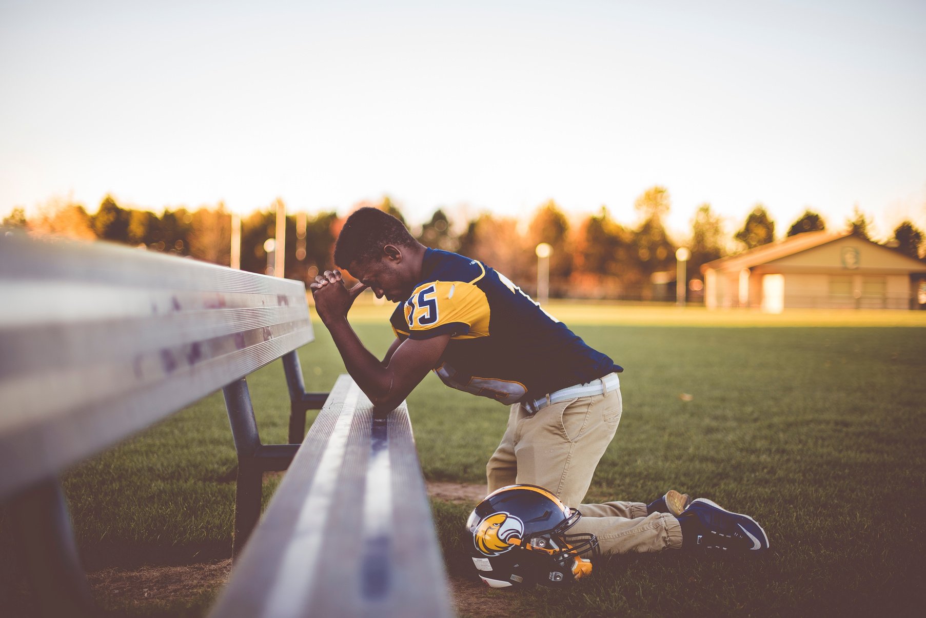 Football Athlete Kneeling and Praying